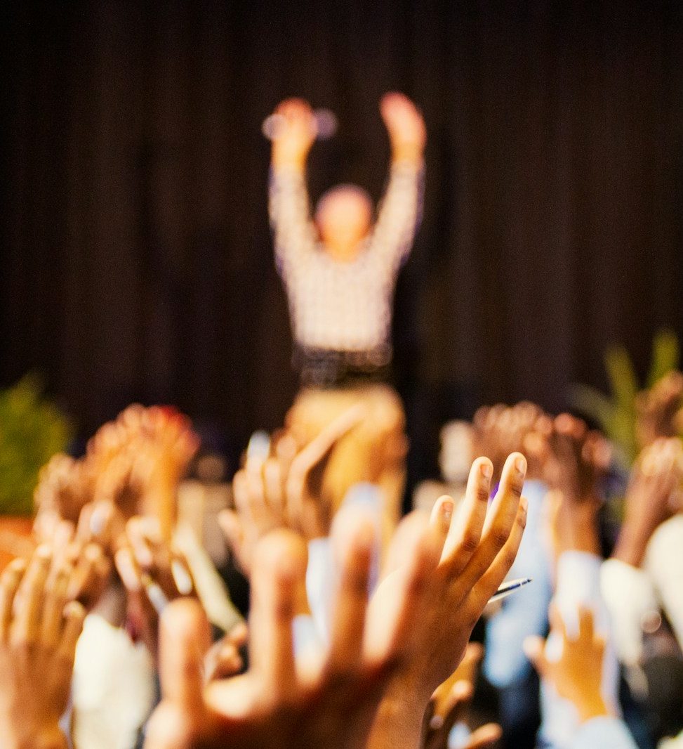 people raising hands with bokeh lights